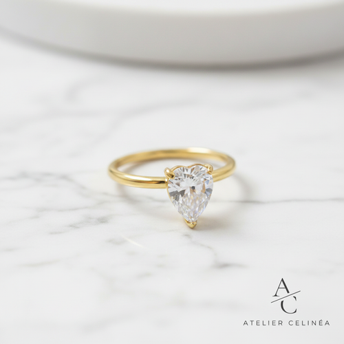 Gold Pear Solitaire Ring op marmer met Atelier Celinéa logo